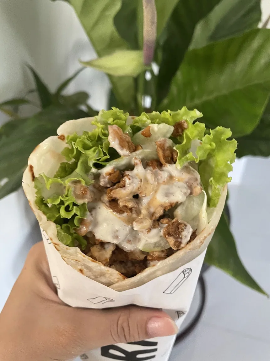 Tapos nang homemade shawarma na hawak sa harap ng mga halaman